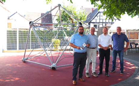 Freigerichts Bürgermeister Waldemar Gogel, Frank Harenburg, Vorsitzender des Fördervereins der Schule am Dorfplatz, Kreisbeigeordneter Jannik Marquart und Schulleiter Holger Kuhn freuen sich über den neuen Fallschutz rund um das Klettergerüst.